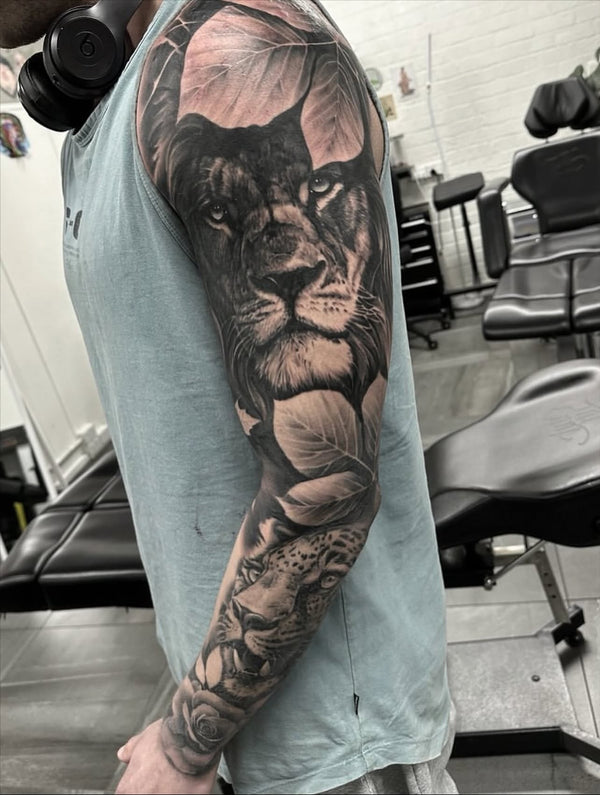 Black and grey realism lion and leopard tattoo on arm