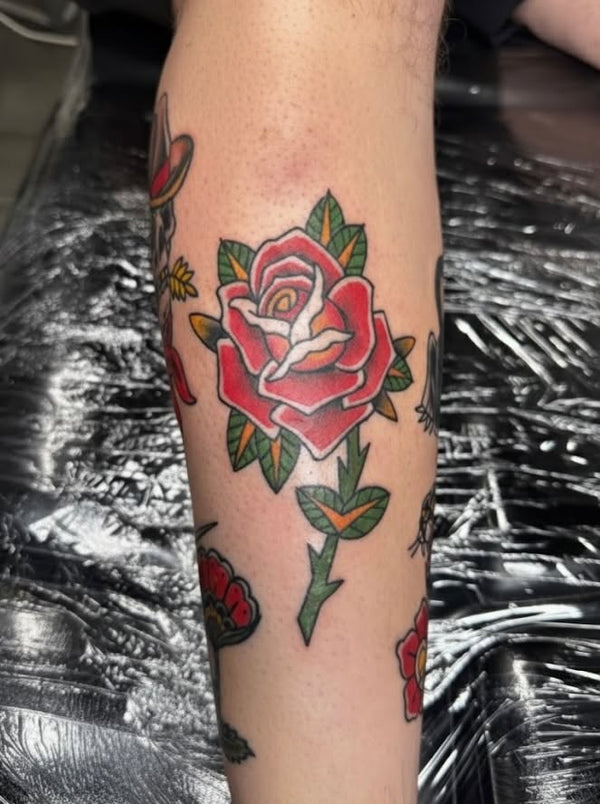 Traditional red rose tattoo on leg